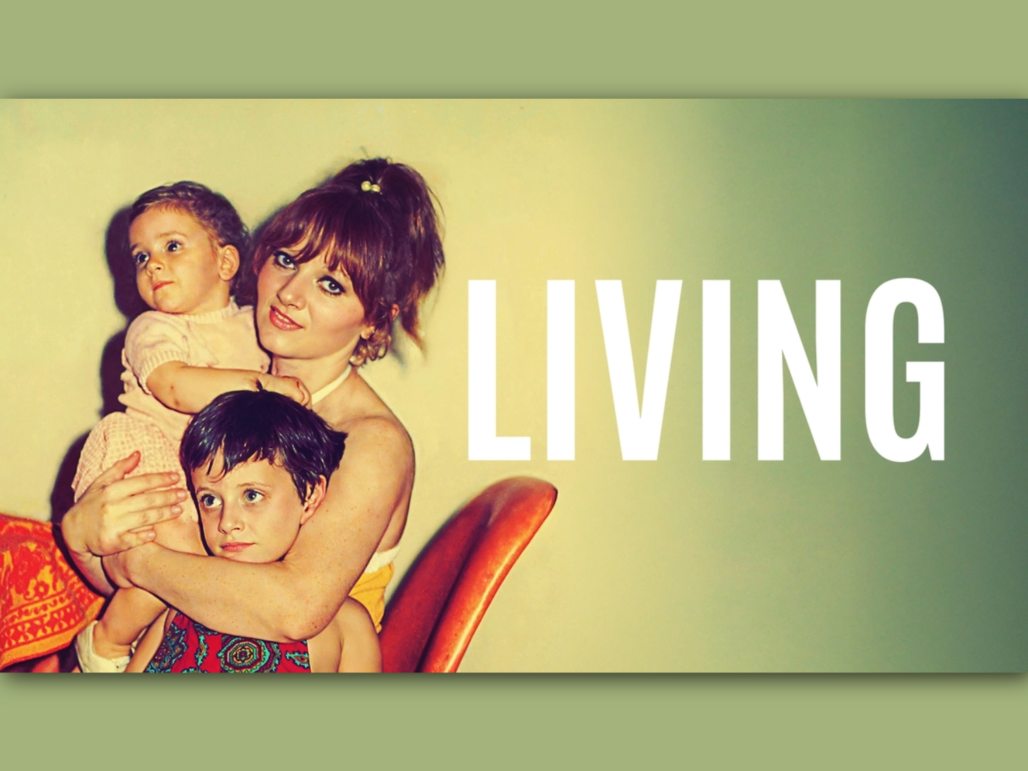 A woman, looking straight at the camera, sits on on chair holding two small children.