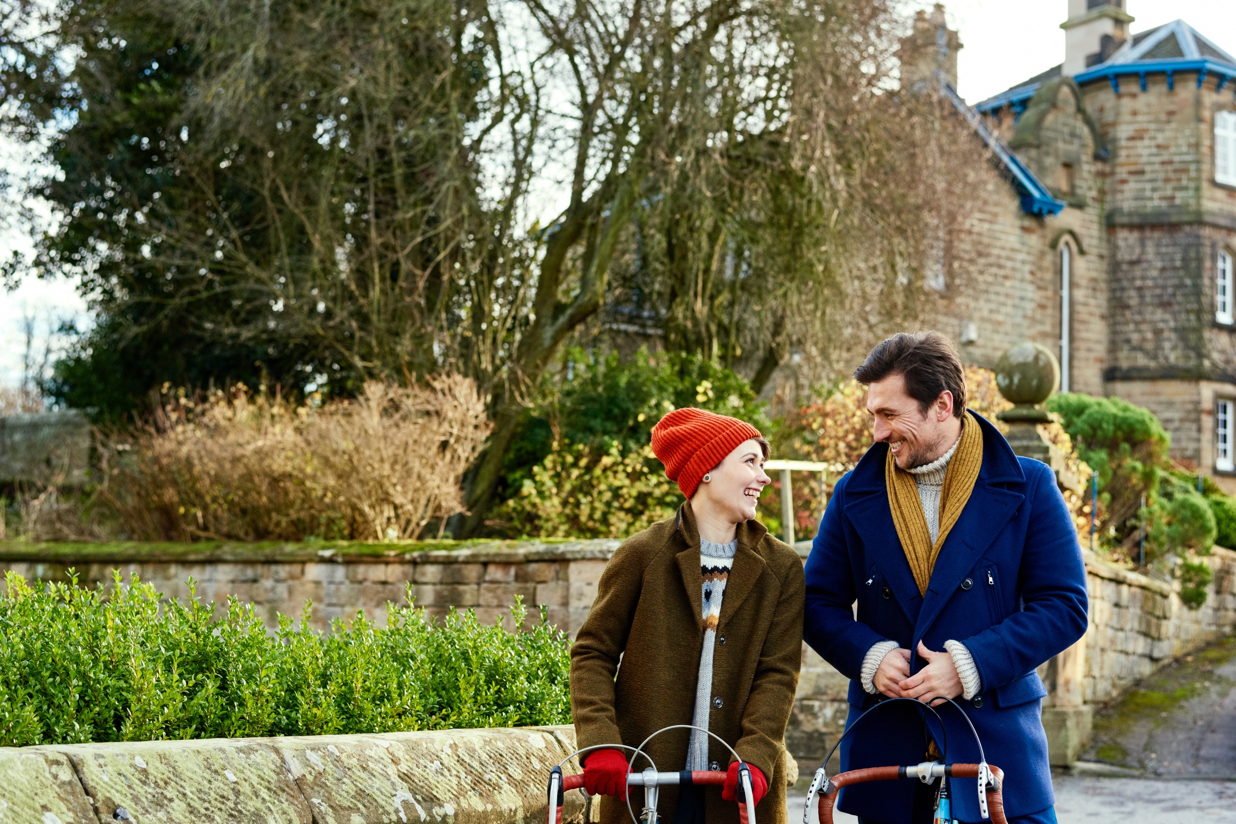 Two people cycling through a village in the Peak District National Park.