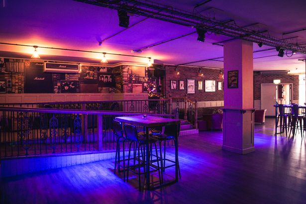 The dance floor and bar at Maida Vale, lit by purple lighting.