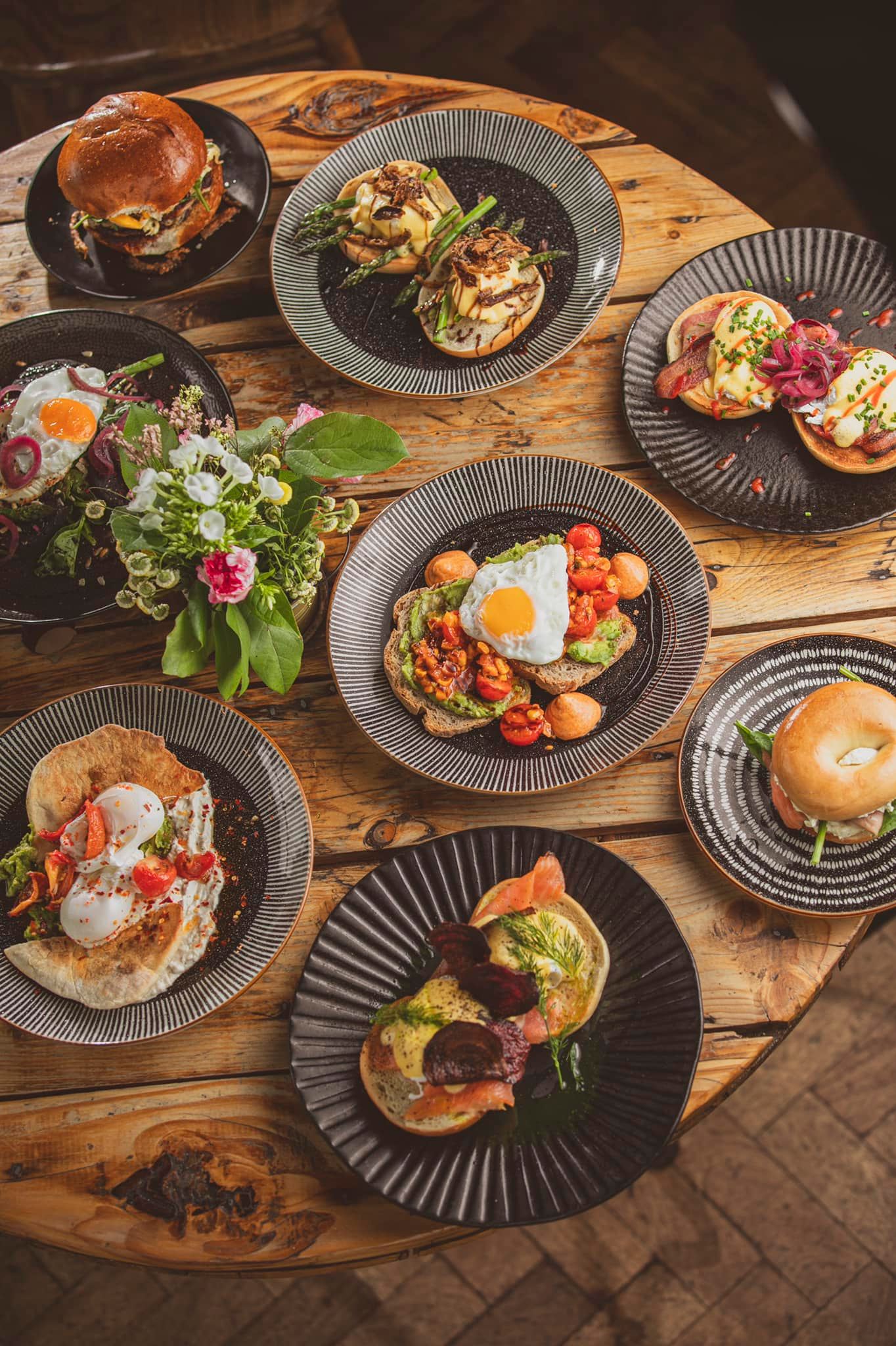 Eight different dishes laid out on a wooden table.