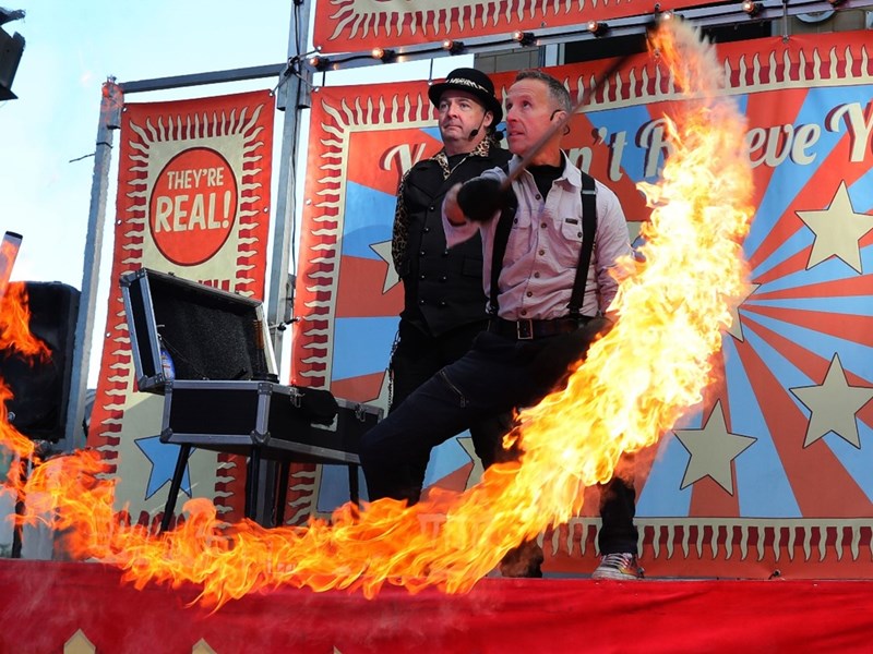 An illusionist creates a ring of fire on stage while an assistant watches on