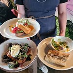 A member of Tamper Coffee staff carrying three plates of food to a table.