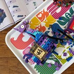 A Lego kit, partly assembled, on a table along side the box and the instruction booklet.