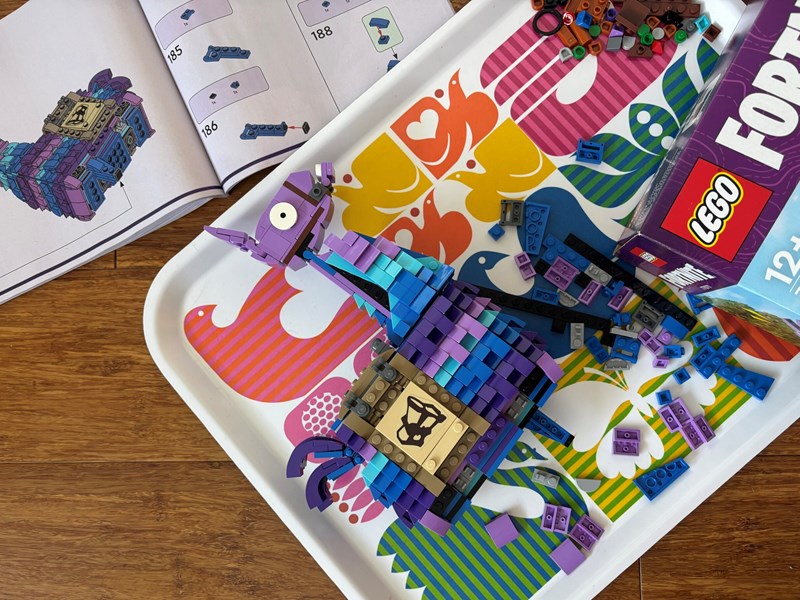 A Lego kit, partly assembled, on a table along side the box and the instruction booklet.