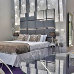 Opulent hotel bedroom at Aston Hall Hotel with king-size bed, cushions, and warm lighting creating a relaxing ambiance.