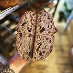 A hand holds a load of bread that has been cut in half.