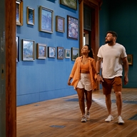 A couple walking through Graves Gallery, in Sheffield, looking at the pictures displayed on the walls.