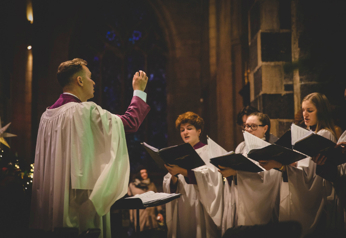 A man conducting a choir in a church.