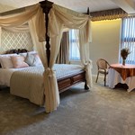 A hotel room with a four poster bed.