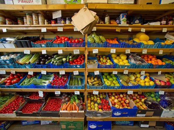 A whole wall of wooden shelving full of organic fruit and vegetables for sale.
