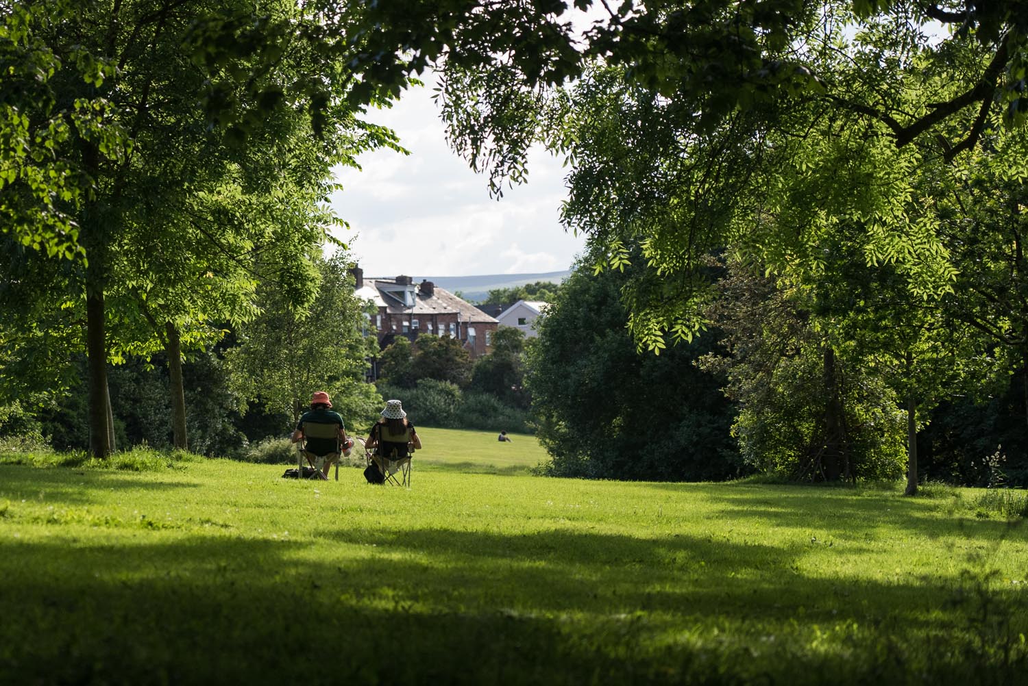 Two people sat in camping chairs, enjoying the sunshine, in Meersbrook Park.