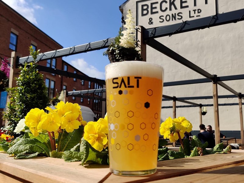 A glass of beer on a table in the beer garden at SALT Sheffield.