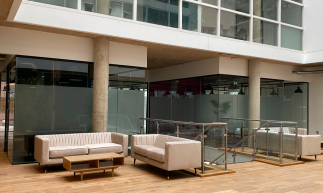 An interior shot of Cubo featuring 3 cream sofas and a low, wooden coffee table. 