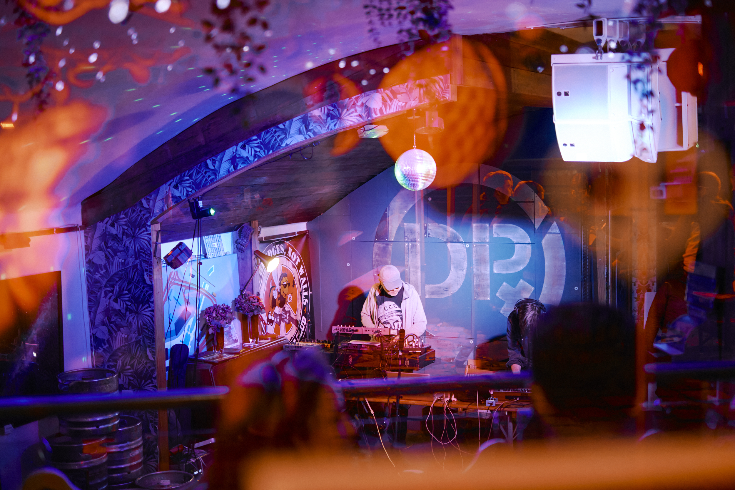 A DJ is standing behind the decks, performing for a club crowd.