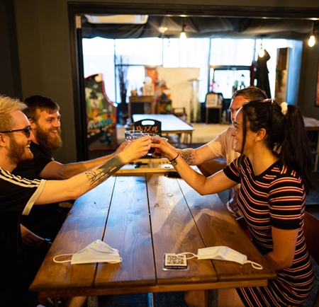 Four people are sat at a wooden table, having a drink and enjoying themselves at Escape.