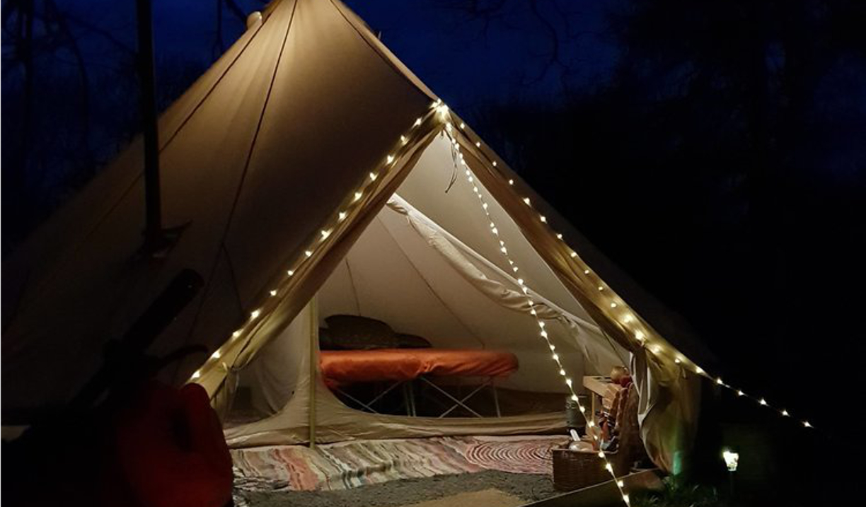 A tent lit up with a string of lights.