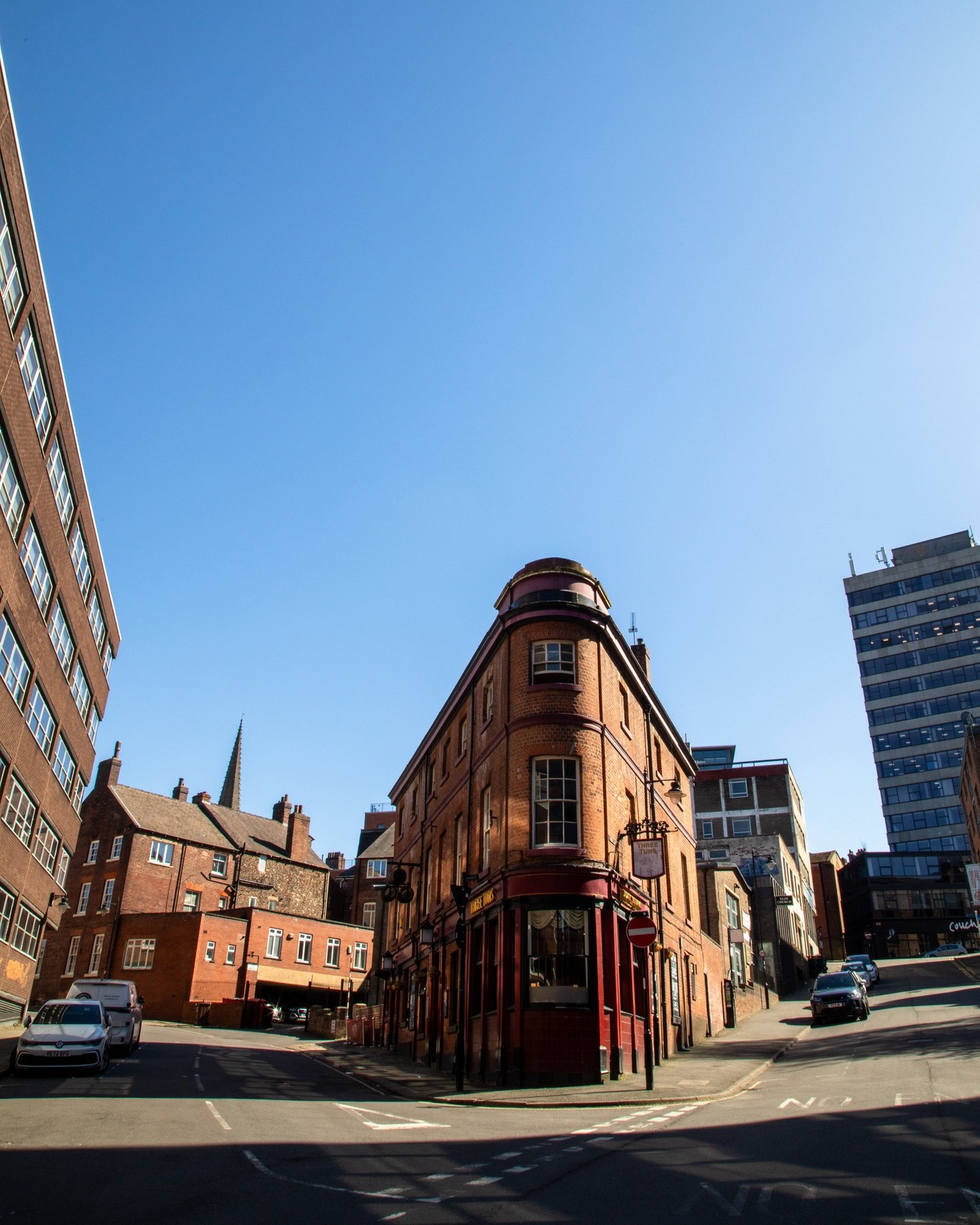 looking up at the angular exterior of The Three Tuns pub against blue skies