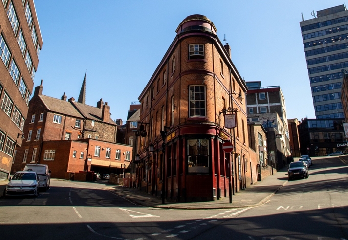 looking up at the angular exterior of The Three Tuns pub against blue skies