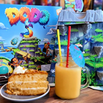 A table at The Dice Box Sheffield with a cocktail, a slice of cake and a game called Dodo.
