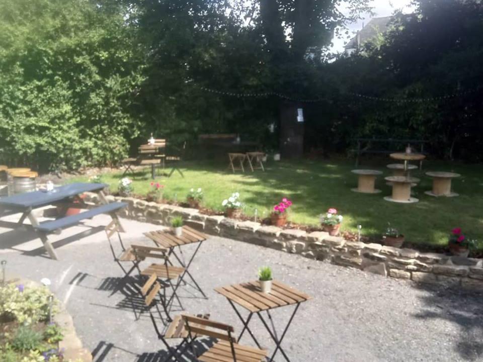 Outdoor garden of The Dalbury & Palmer Hotel featuring tables, chairs, and seating for guests.