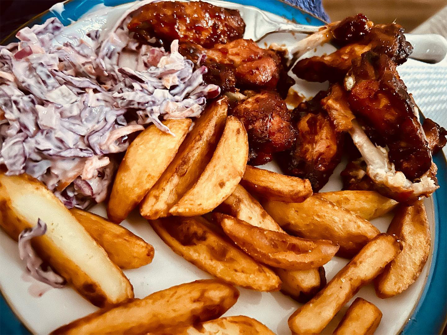 A plate of chicken in sticky BBQ sauce, chips and coleslaw at the Dog & Partridge pub.