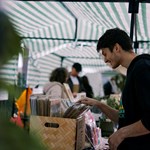 A man wearing a hoodie browsing through a box of vinyls