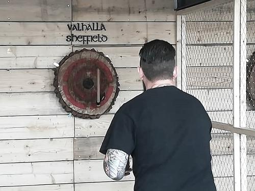 A man throwing an axe at a target hung on a wall.