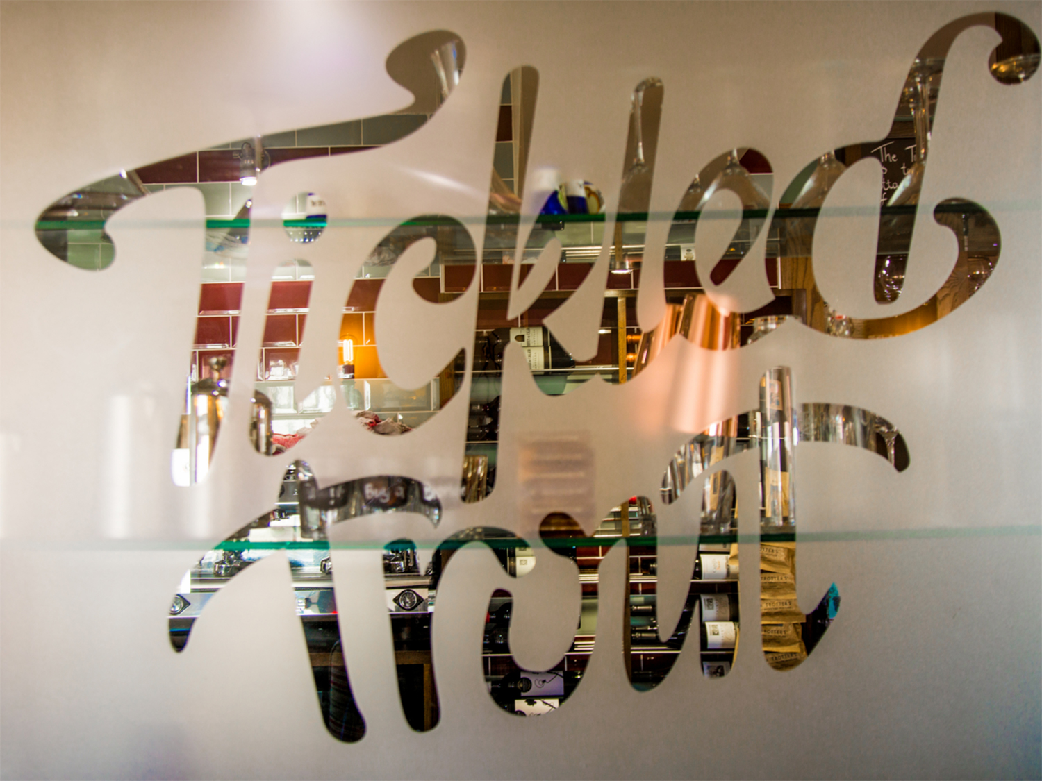 The Tickled Trout logo etched in a frosted glass window.