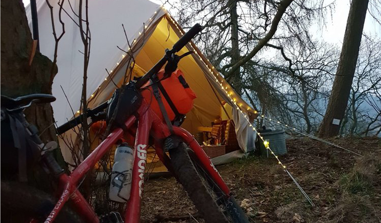 A bike and a tent in the countryside.