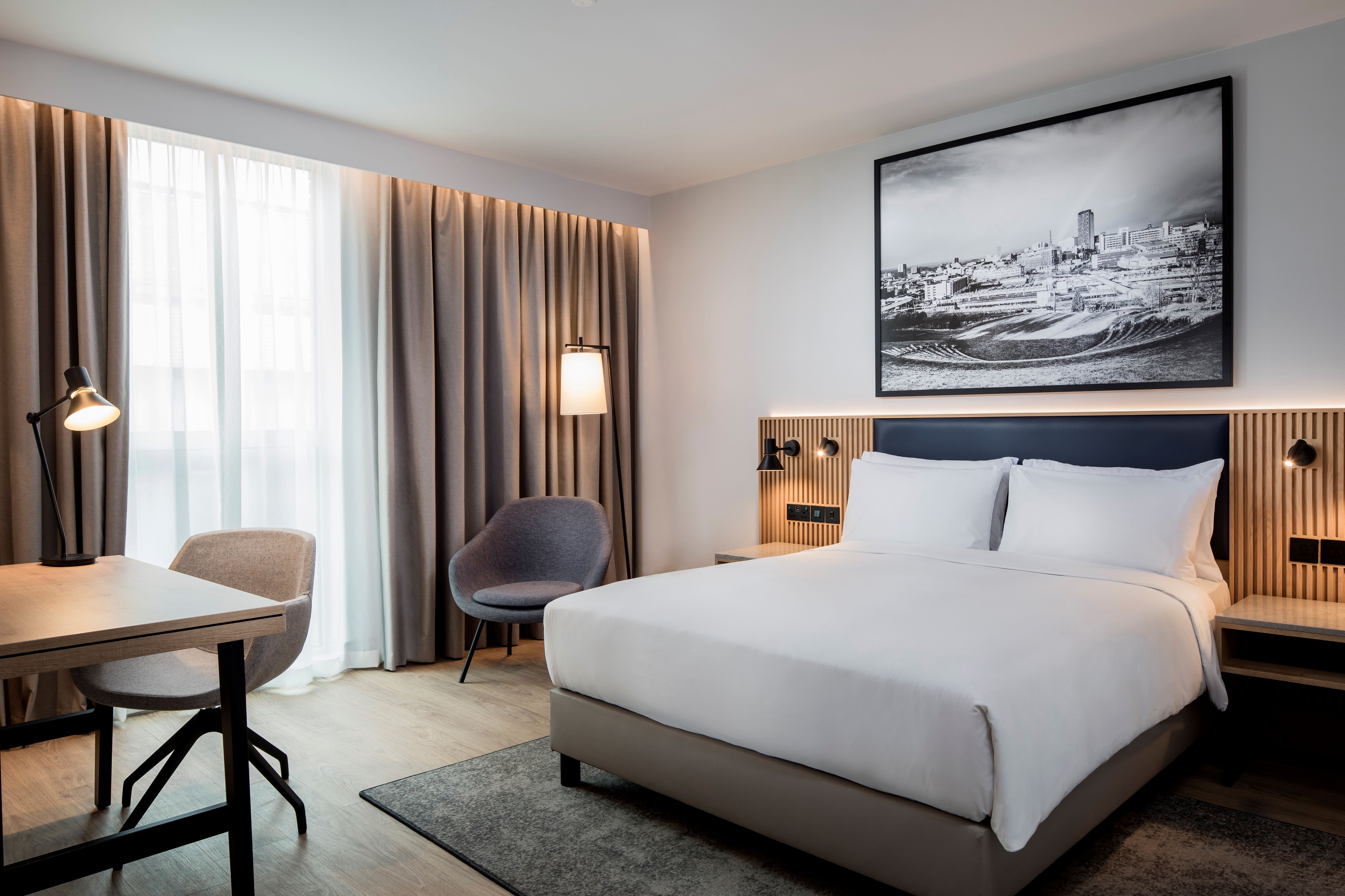 Modern bedroom with a double bed and a local picture hanging on the wall and cool lighting.