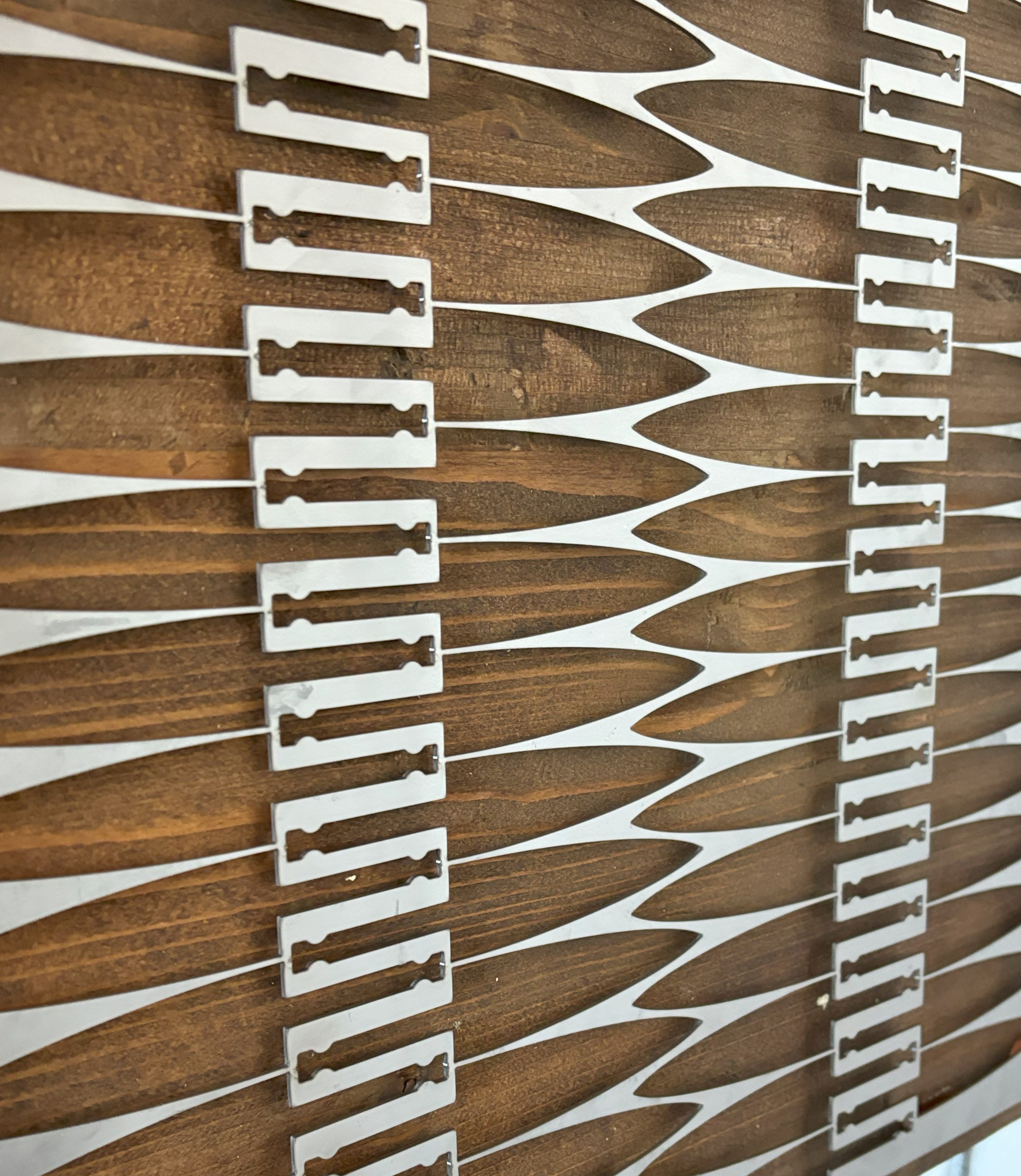 Close-up of a decorative panel featuring alternating wooden and metal elements in a repeating geometric pattern with elongated shapes and cut-out details