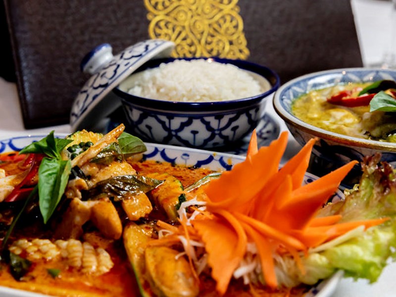 Three colourful dishes of food on a table at the All Siam Thai Restaurant.
