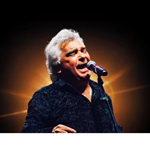 A photograph of Nicolas Reyes, lead singer of the Gipsy Kings, singing live in concert.