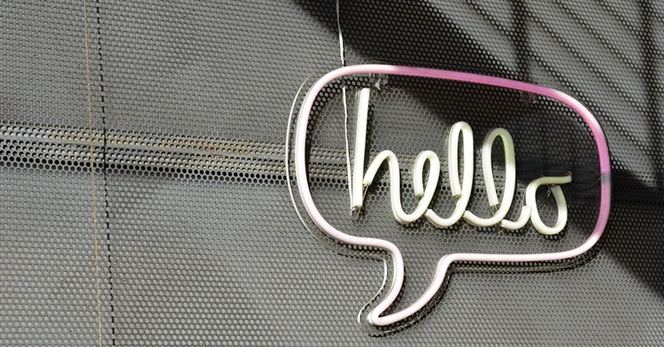 A neon sign on a wall that is a speech bubble with the word 'hello' in it.