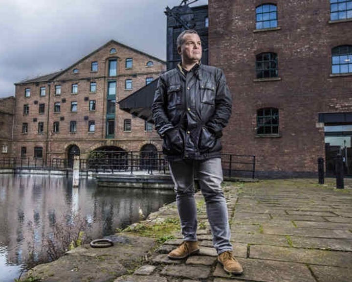 A man dressed in a dark jacket and black jeans stand on Victoria Quays in Sheffield.