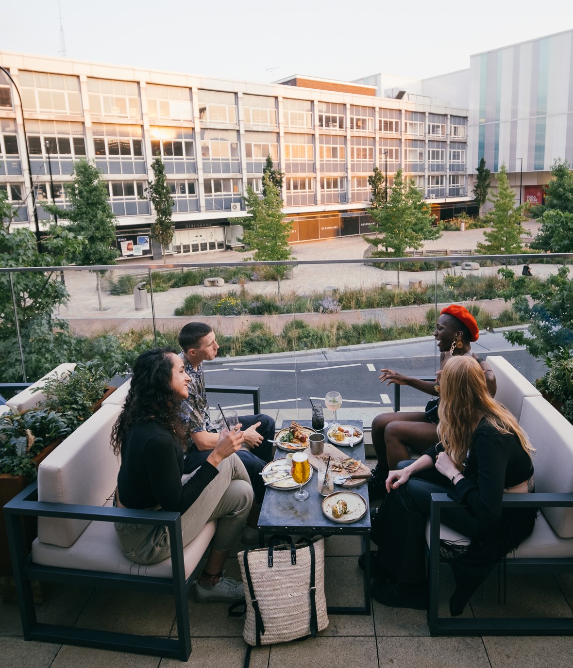 Four people are sat outside on the terrace at the restaurant The Furnace enjoying a meal.