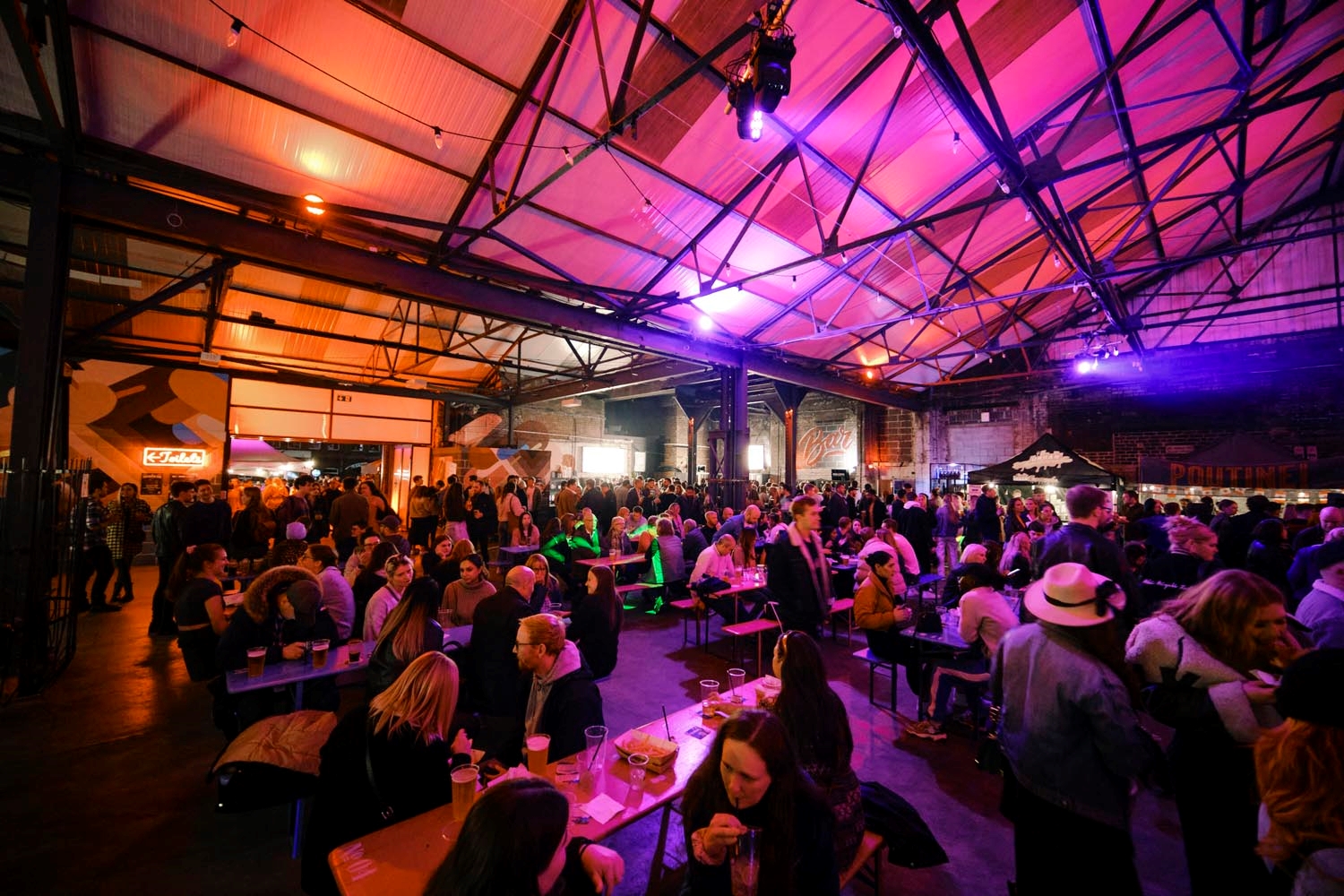 A view inside the Peddler market, there are lots of people seated at tables, eating and chatting.