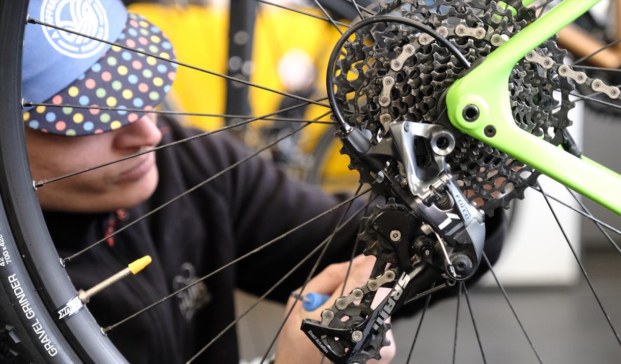 A man servicing the gears on a bike.
