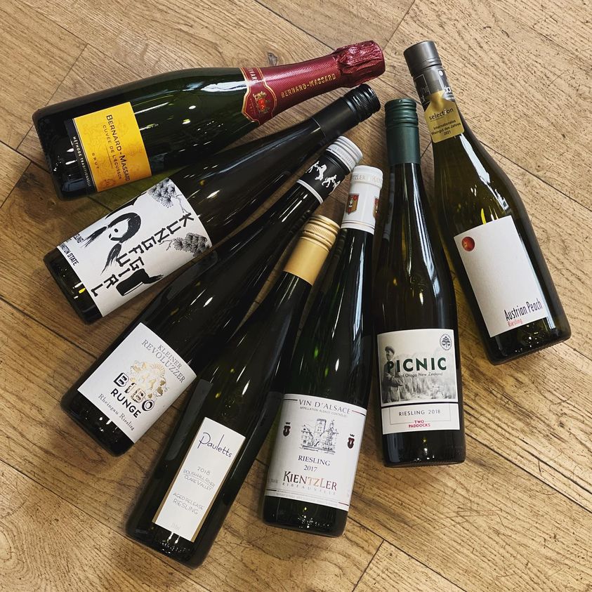 Seven bottles of wine arranged on a wooden surface.