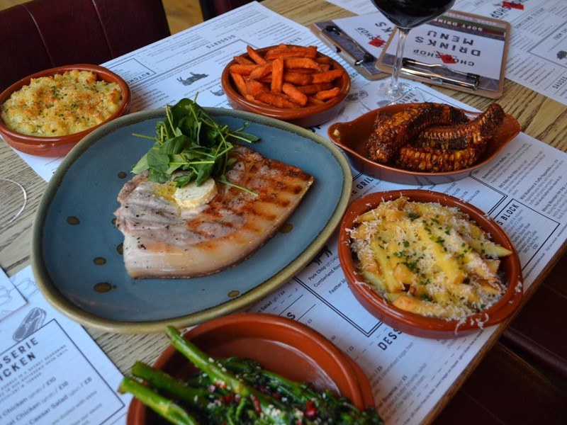 A table set up with meals for 4 people at the Chop Shop Bar & Grill..