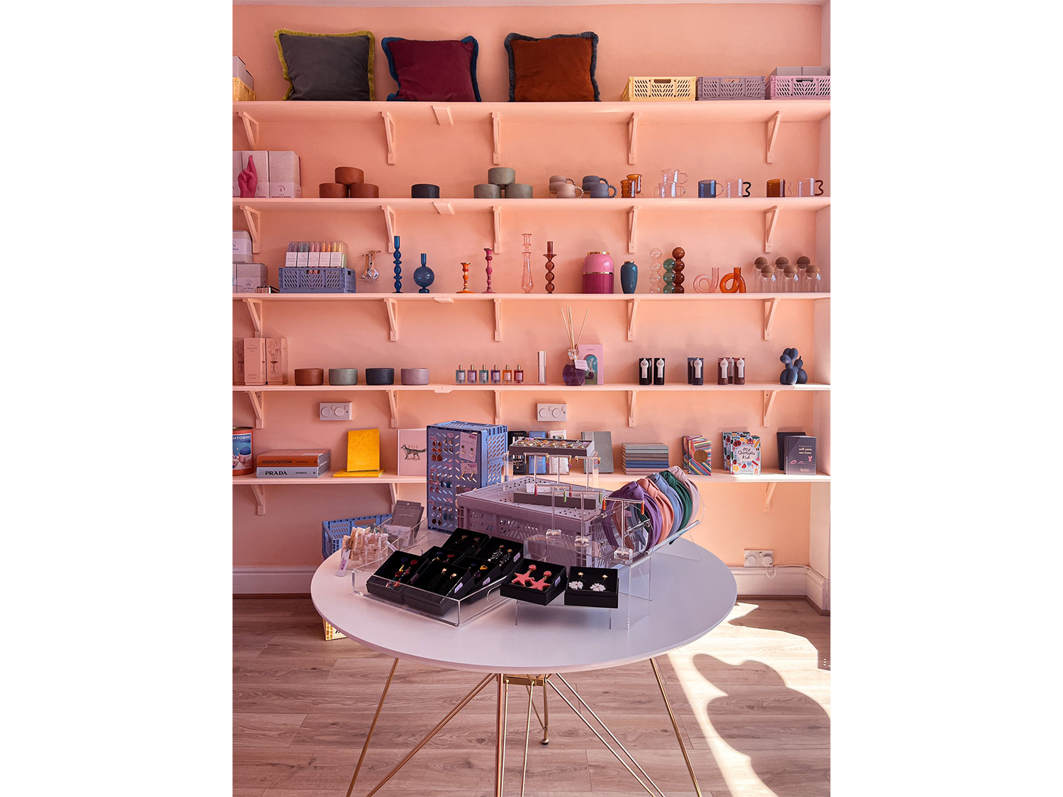 Interior shot of The Stylists Lifestyle Store with a table and shelving displaying various house wares.