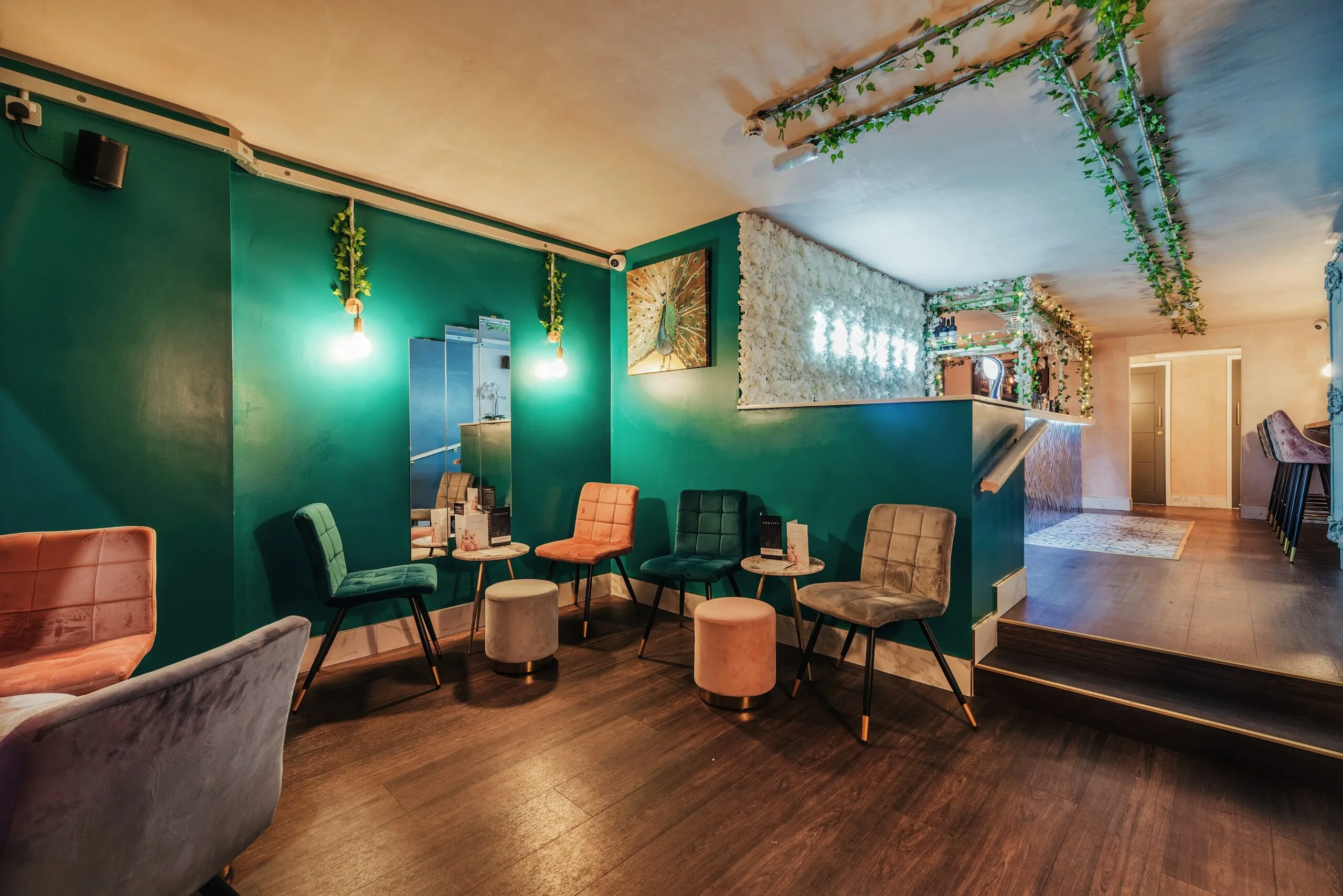 The interior of a bar, with green walls and lots of table and upholstered chairs.