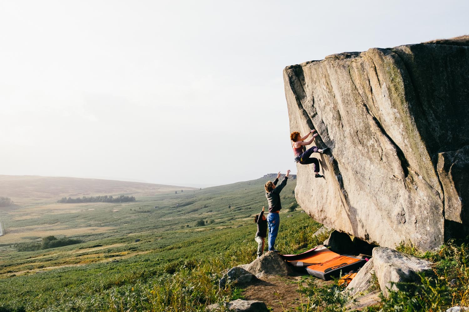 Three people bouldering in the peak district. 
