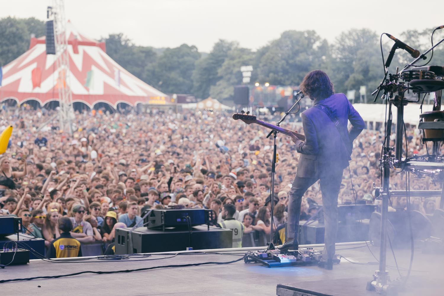 A photo taken from the back of the main stage at Tramlines Festival, looking out over the crowd with a man playing a bass guitar in the foreground.