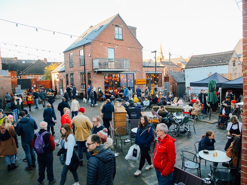 A large crowd of people looking round an outdoor market on Sharrow Vale Road in Sheffield.