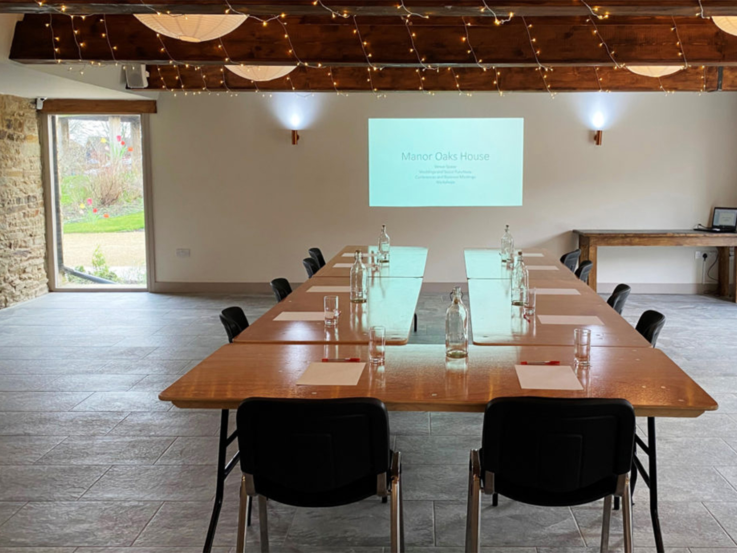 A room set up for a meeting, with a projector screen showing a slide deck, at Manor Oaks House.