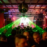 A crowd dances to a DJ, with green lazers lighting the dancers.